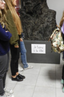 Napis w języku francuskim umieszczony na czarnej rzeźbie, popiersie C. K. Norwida. Fotografia ucieła pół głowy rzeźbie. Obok stoją trzy uczennice. Na ścianie okazale dekoracje. Kliknięcie w miniaturkę obrazka spowoduje wyświetlenie powiększonego zdjęcia.