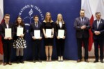 Anna Karpińska z dyplomem w rękach stoi na scenie Sali Błękitnej razem z grupą stypendystów i urzędników państwowych: Lech Sprawka, Przemysław Czarnek. Kliknięcie w miniaturkę obrazka spowoduje wyświetlenie powiększonego zdjęcia.